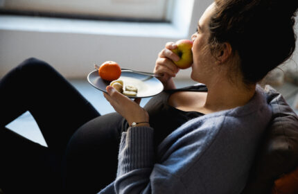 Zwangere vrouw neemt een hap van een appel en heeft andere gezonde voeding op haar bord