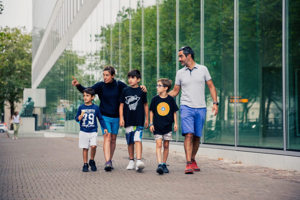 Vader en moeder lopen met drie zoons op straat in Den Haag. Moeder wijst iets aan